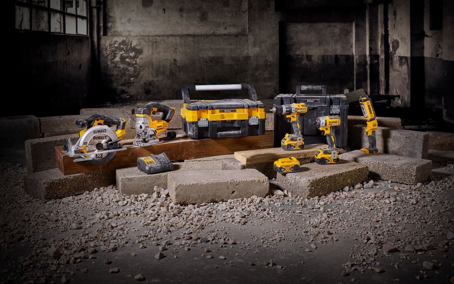 DEWALT cordless tool set with toolbox and batteries displayed on blocks in an industrial setting.
