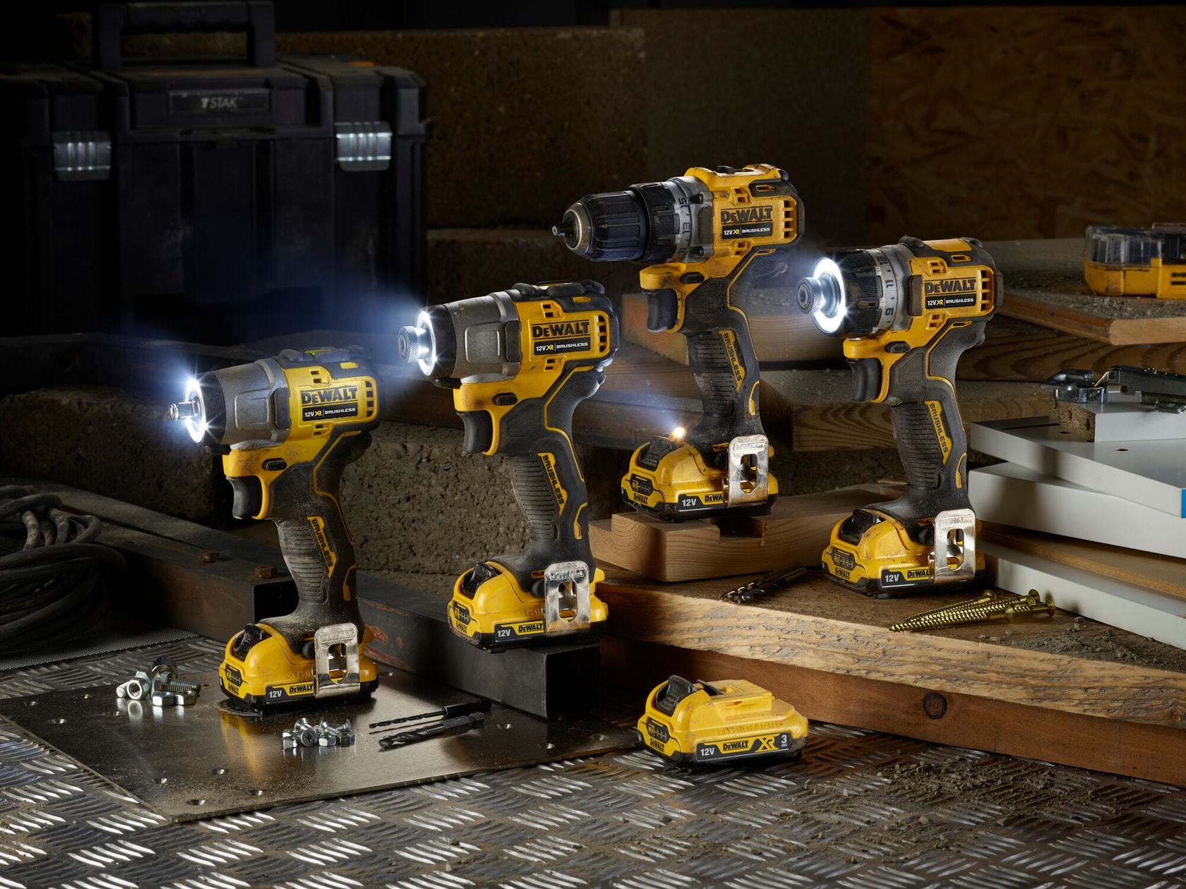 Three DEWALT cordless power tools with LED lights on, shown in a workshop setting with accessories and batteries.
