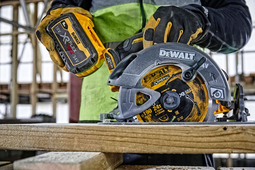 DEWALT cordless circular saw cutting wood, person in gloves operating tool at construction site.