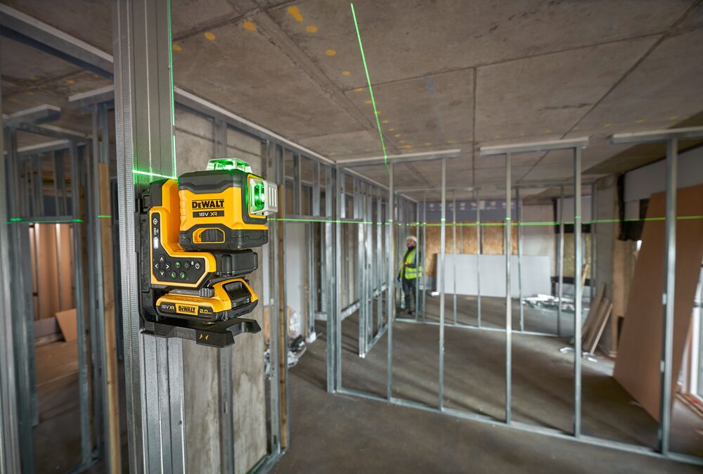 DEWALT green laser level mounted on metal stud for construction alignment in an unfinished building.