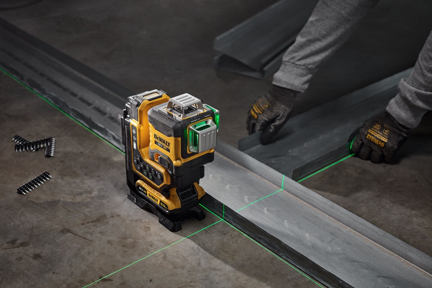 DEWALT laser level projects green lines onto metal tracks for alignment during construction work.