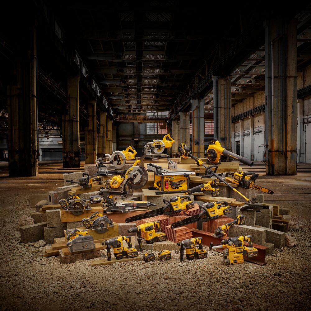 A large assortment of DEWALT power tools, including saws, drills, and other equipment, are displayed on a pile of construction materials in an industrial warehouse setting.